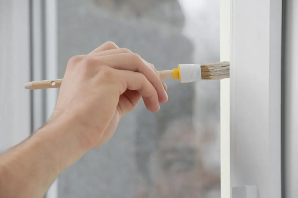 Hand of young worker painting window frame